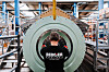 Ansatt foran en stor rund industrikomponent i et verksted hos Bergen Engines.