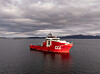 Rødt offshore subseafartøy fra DOF seiler på rolig sjø under overskyet himmel.